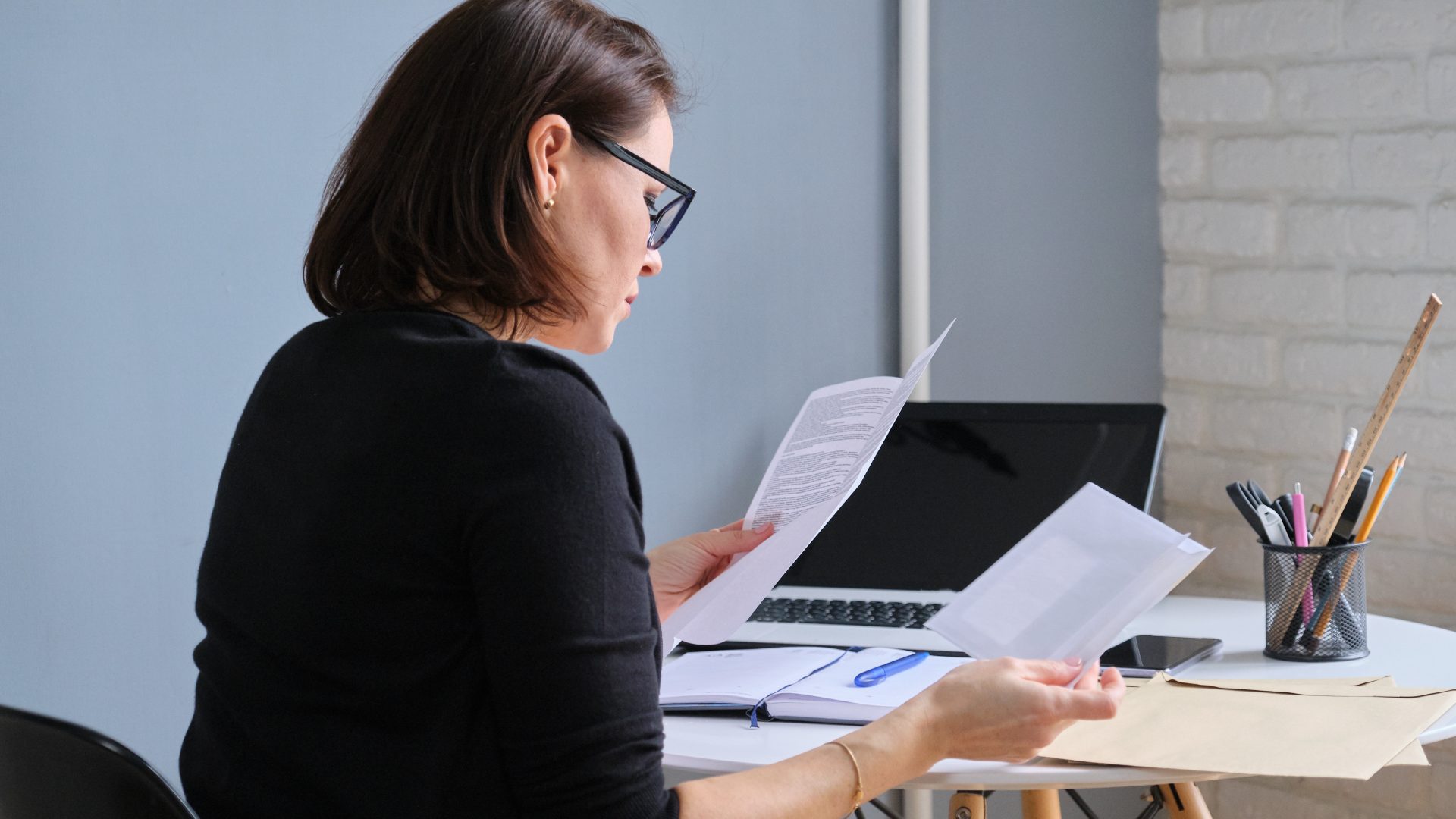 Woman looking at household bills sat at her desk